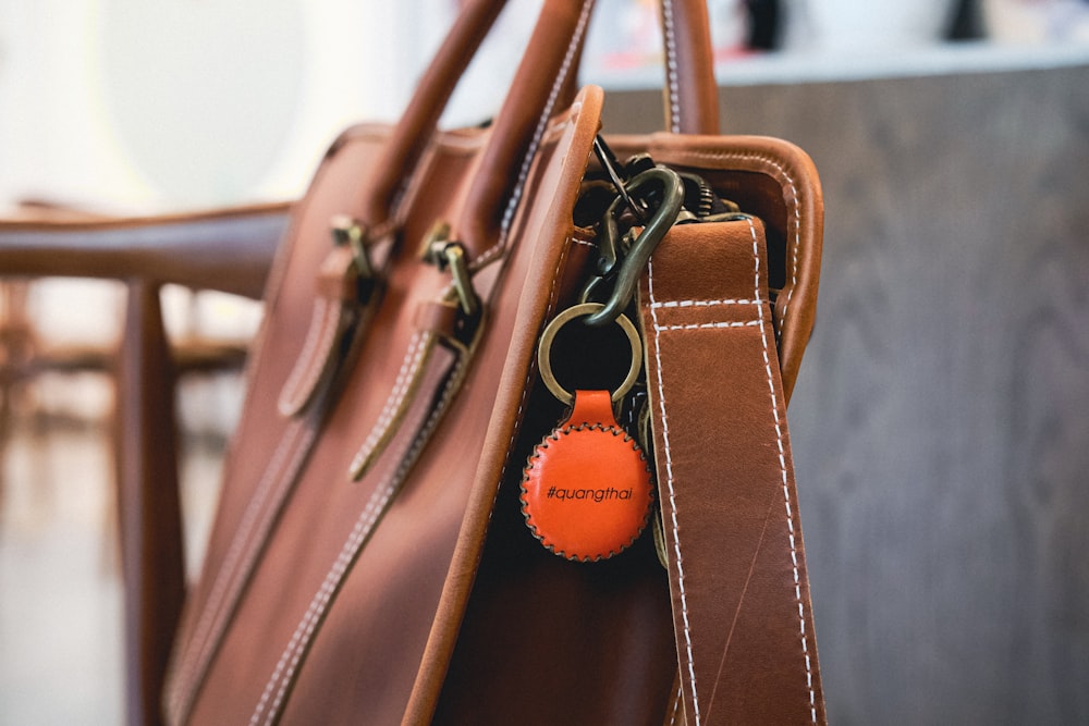 a brown leather bag with a keychain hanging from it