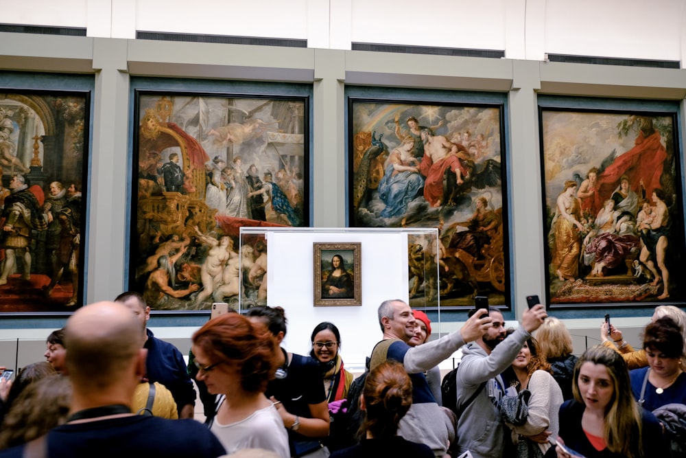 a group of people standing in front of paintings
