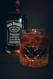 a glass of whiskey next to a bottle of jack daniels