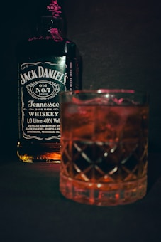 a glass of whiskey next to a bottle of jack daniels