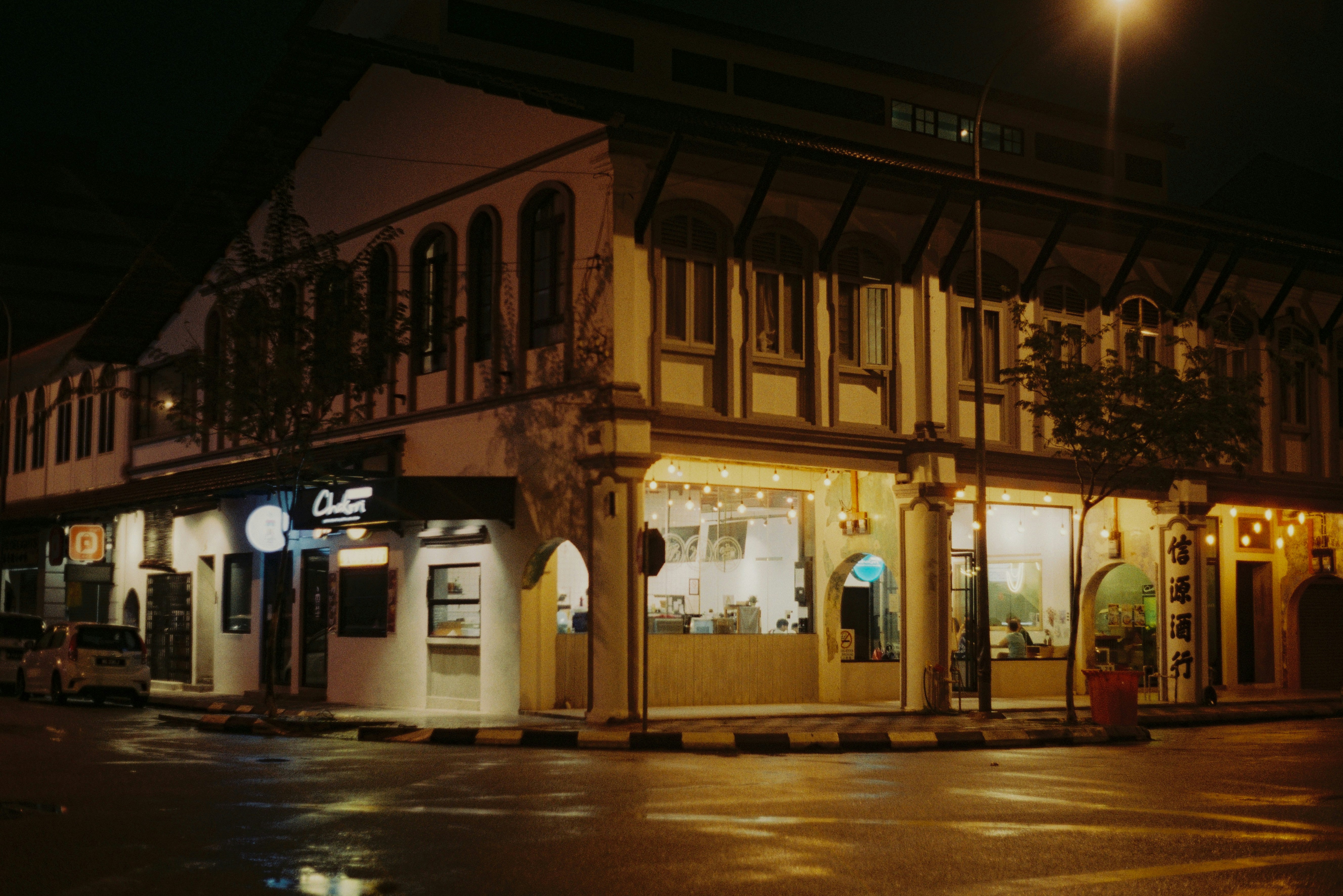 a street corner with a building lit up at night, 
