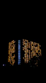Evening view of Wisma Equity with illuminated interiors glowing through the brutalist structure.