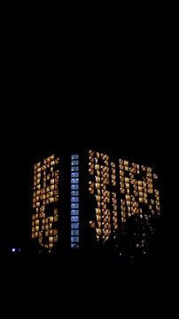 Night view of a sleek high-rise with illuminated golden windows.