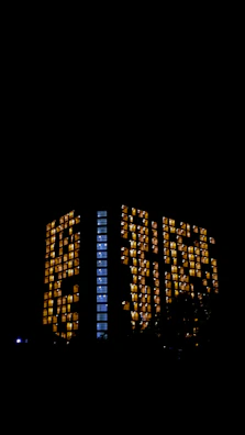 Evening view of Wisma Equity with illuminated interiors glowing through the brutalist structure.