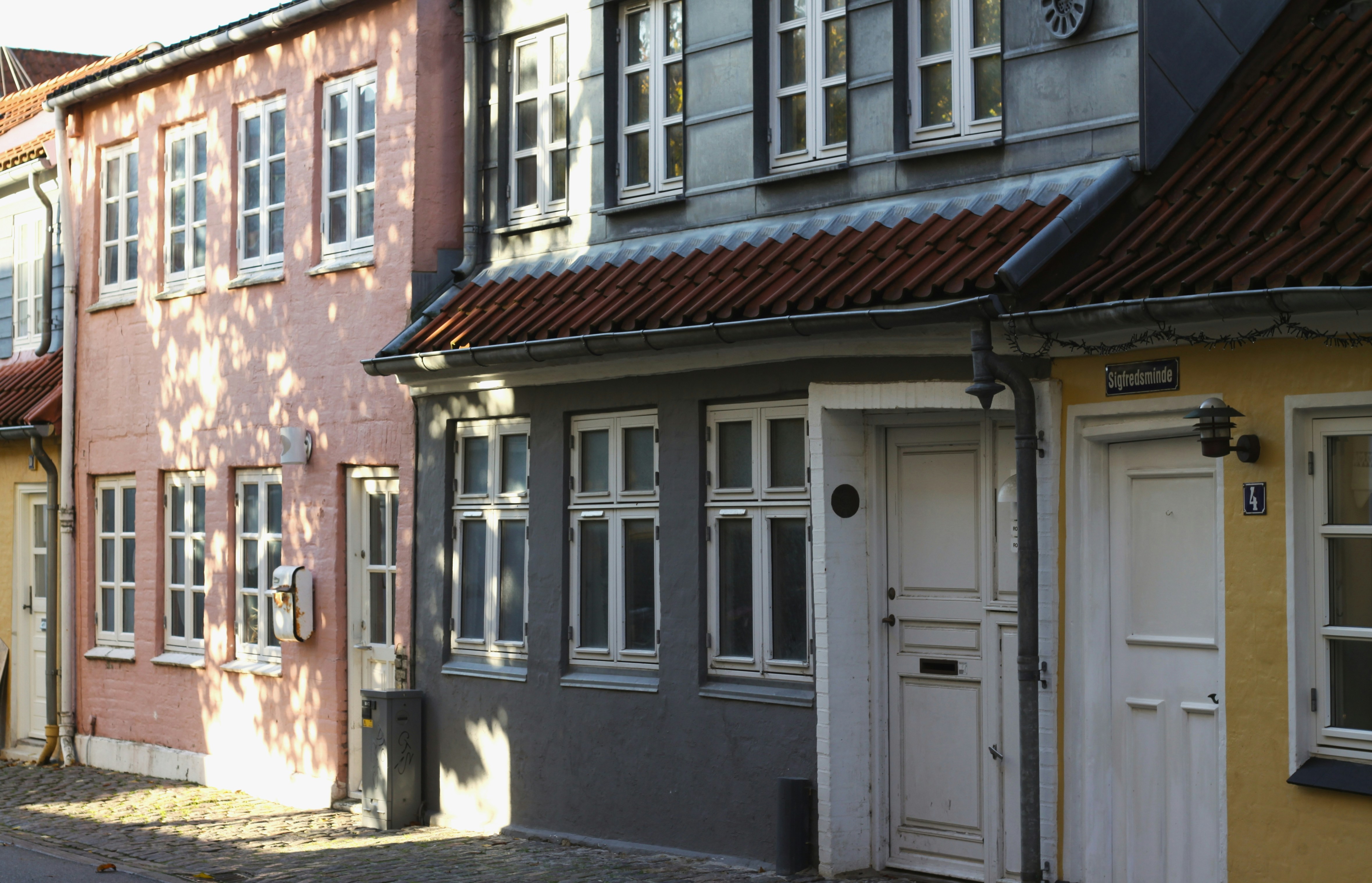 a row of buildings with white doors and windows, caught some sun
