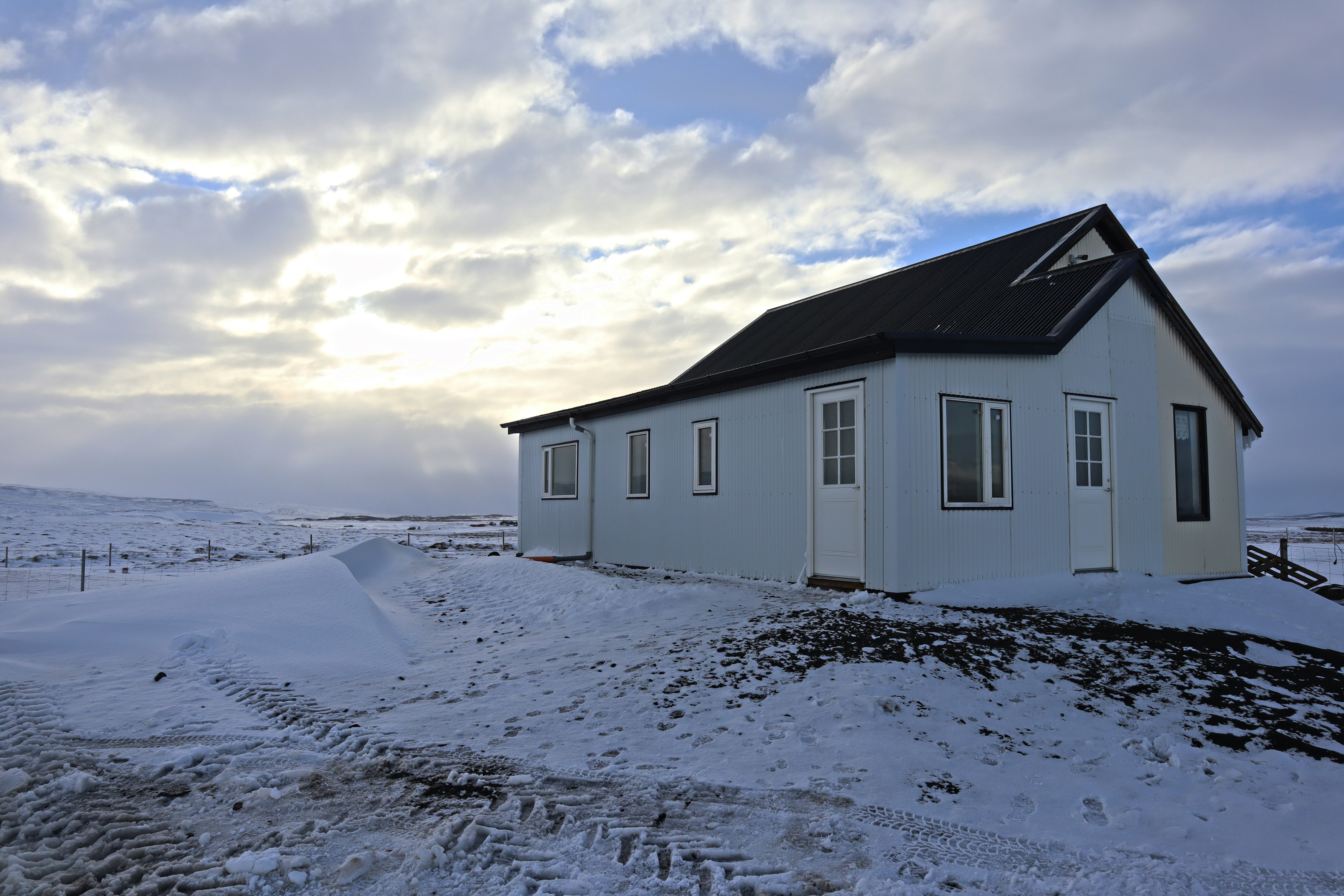 a small white house sitting on top of a snow covered hill