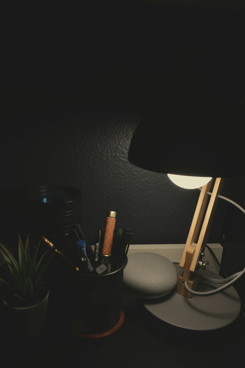 a desk with a lamp and some pens and pencils