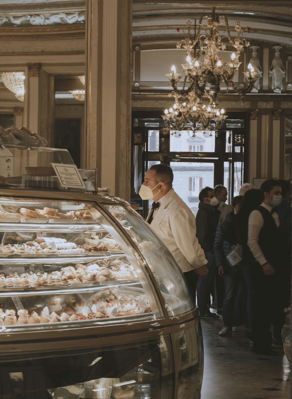 a man wearing a face mask standing in front of a bakery