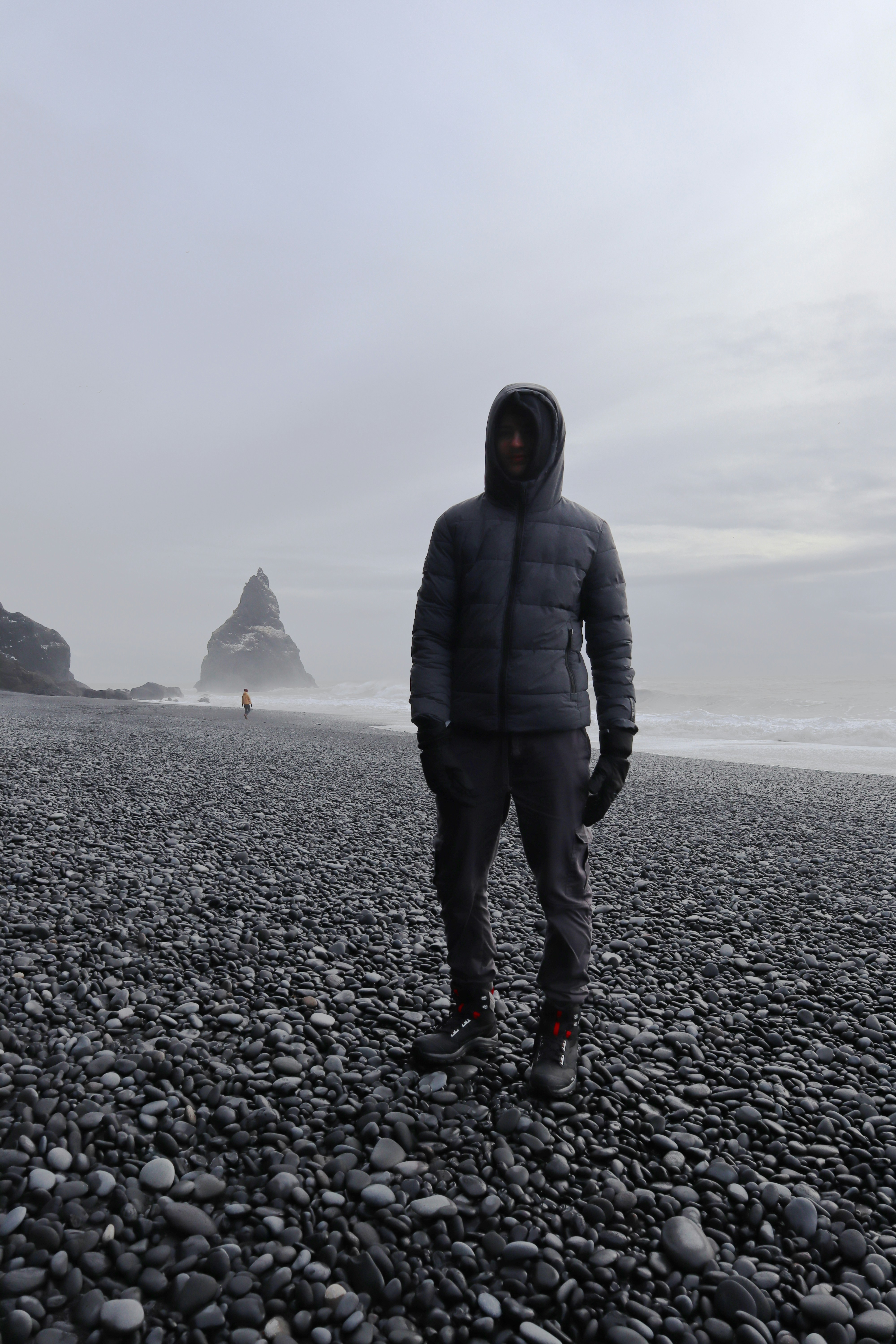 Foto Un hombre parado en una playa rocosa junto al océano – Imagen ...