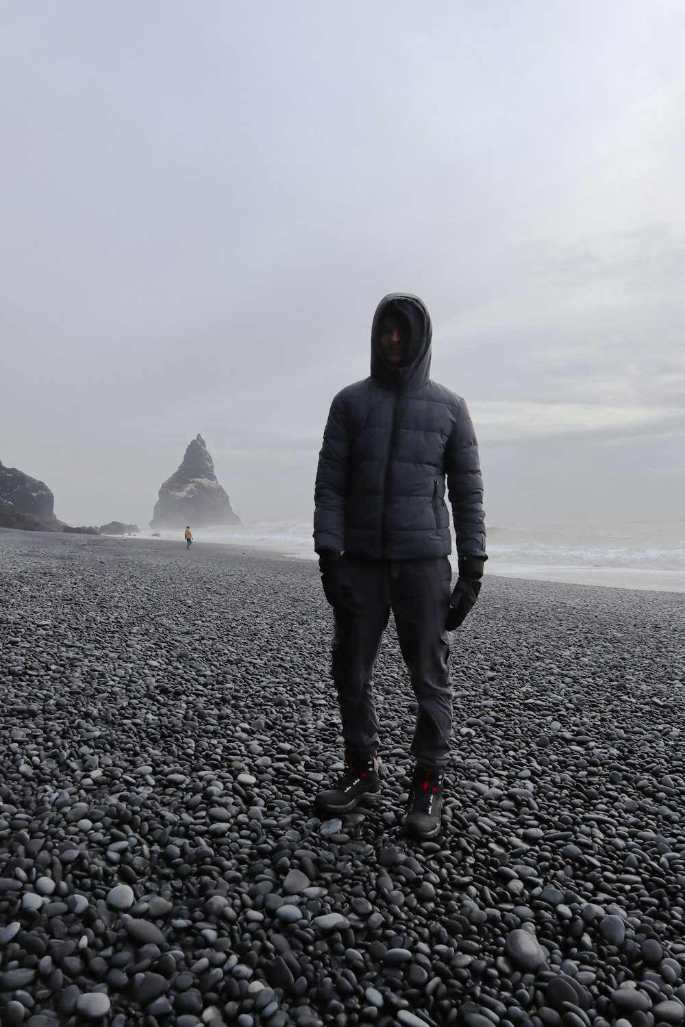 a man standing on a rocky beach next to the ocean