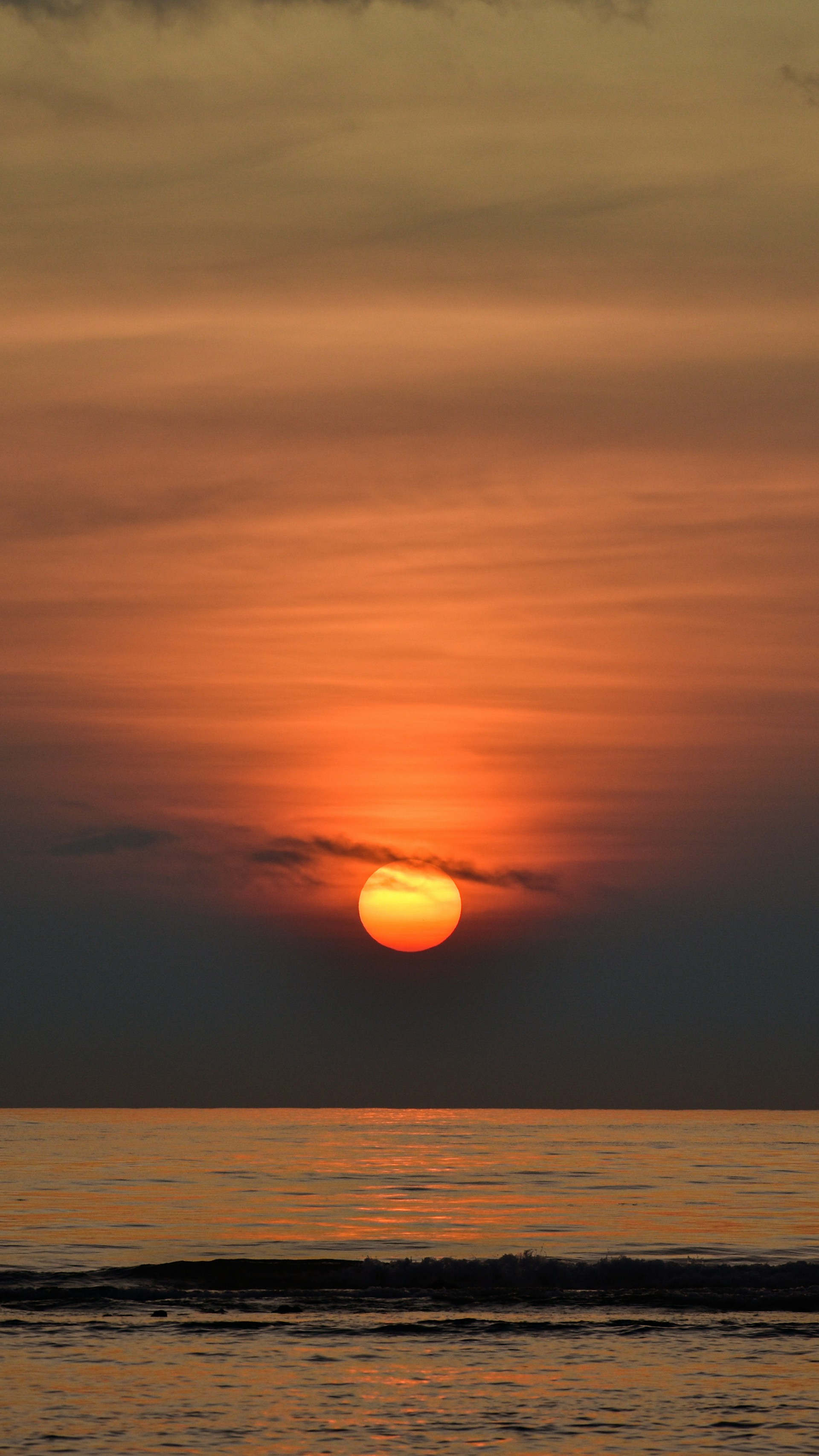 the sun is setting over the ocean on a cloudy day