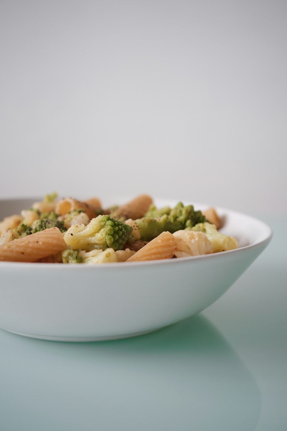a white bowl filled with pasta and broccoli