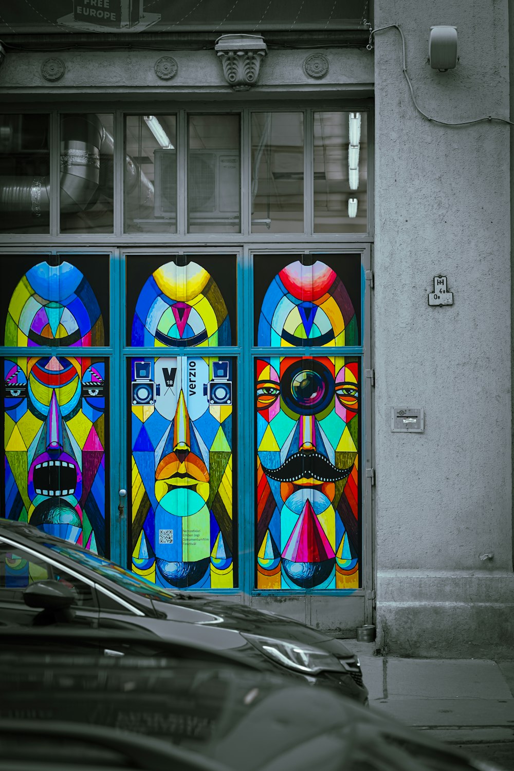 a car parked in front of a building with a colorful mural on the side of