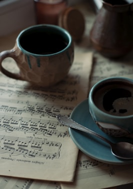 two cups of coffee sit on a sheet of music