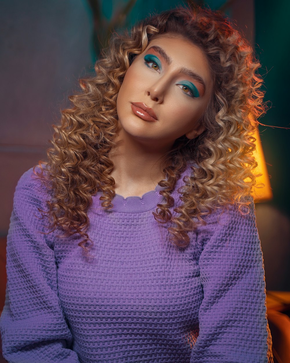 a woman with curly hair wearing a purple sweater