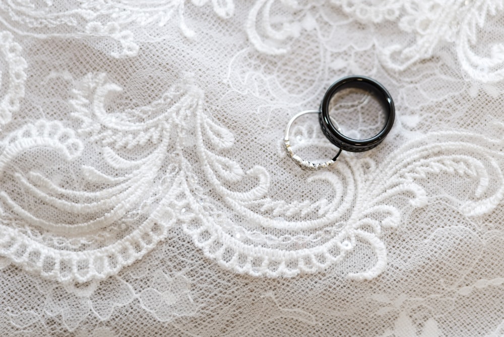 a pair of black rings sitting on top of a white lace
