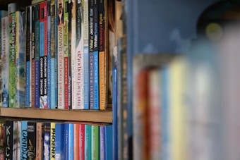 A shelf filled with various books is organized neatly. The spines show different colored covers and titles, with a focus on a range of literature, including works by Michael Morpurgo and C.S. Lewis. The books are tightly packed, displaying an eclectic collection.