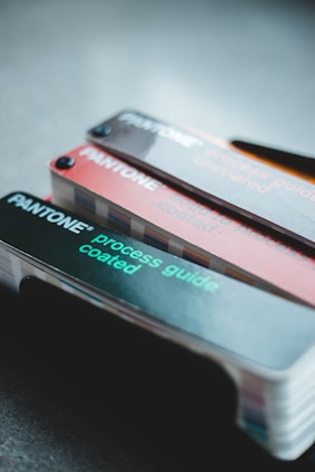 A set of Pantone color guides is displayed, featuring both coated and uncoated process guides. The guides are fanned out slightly, showcasing a range of color swatches. The text on the guides is visible, with the brand name and type of guide clearly marked.