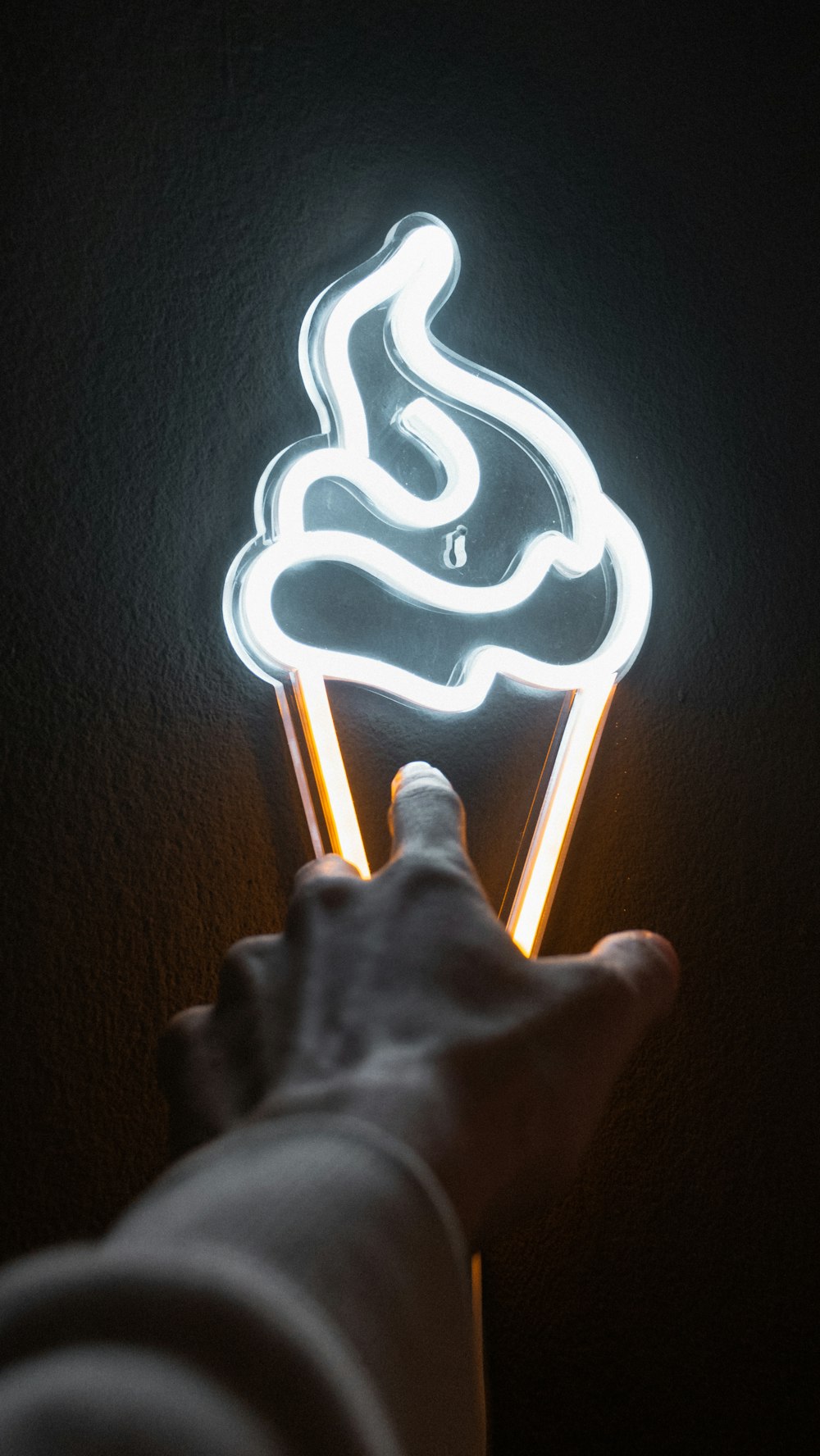 a hand holding a lit up ice cream cone