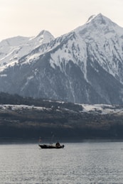 a boat in a large body of water with a mountain in the background