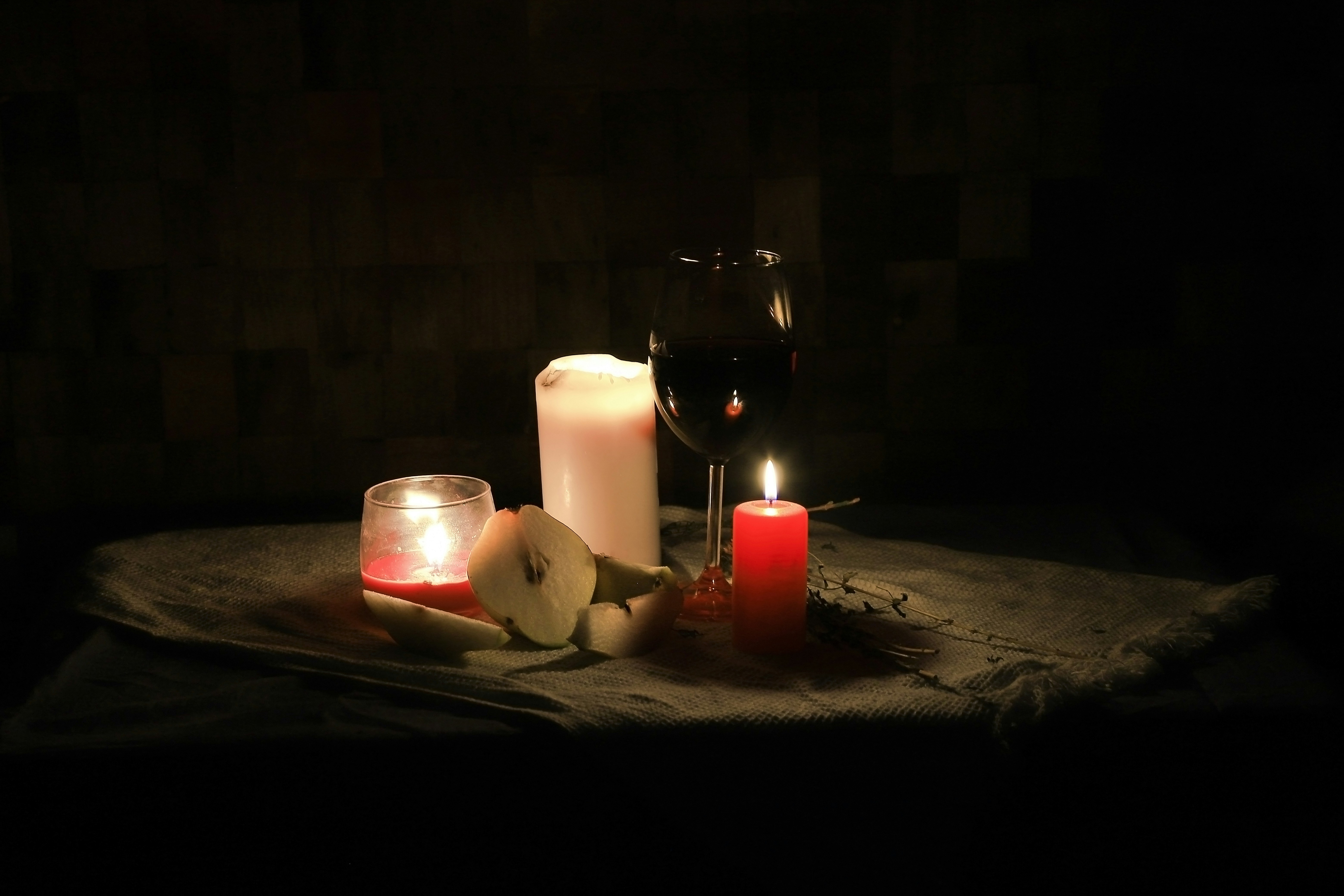 a table topped with candles and fruit next to a glass of wine