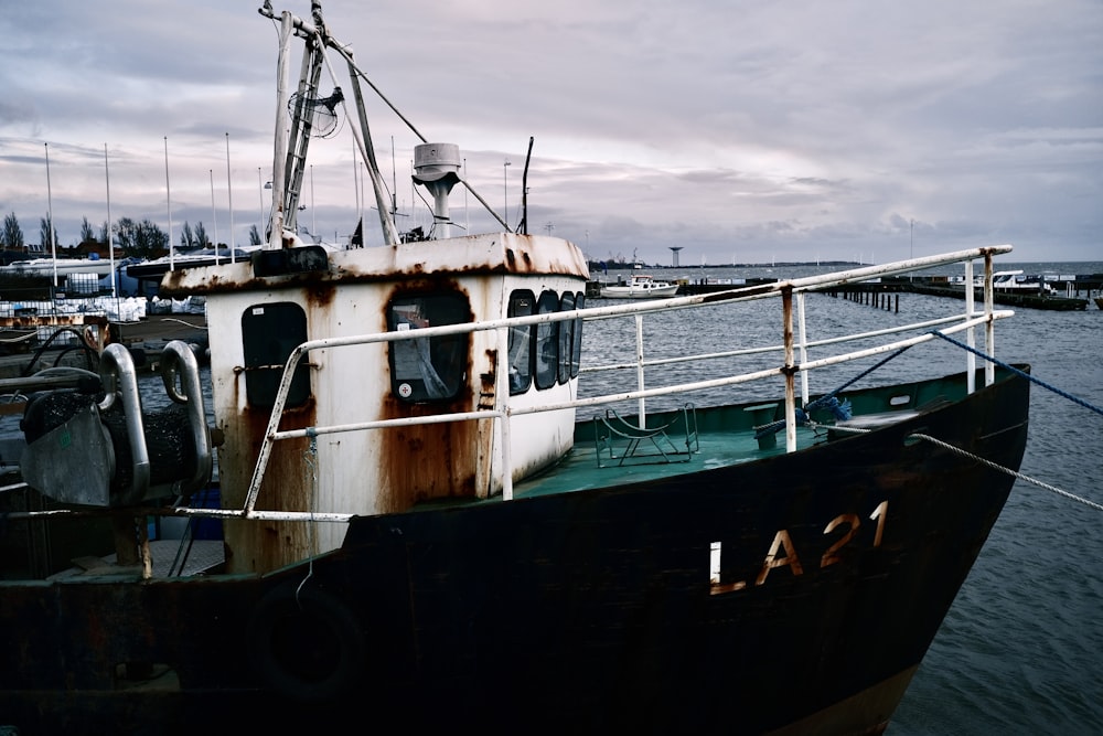 a rusted boat docked at a pier on a cloudy day