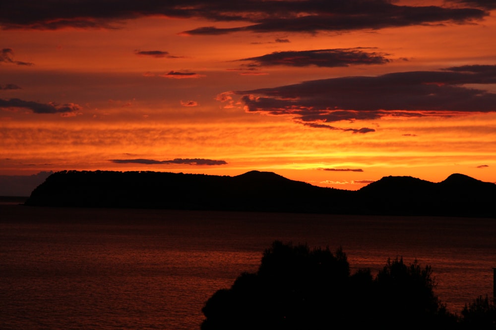 a sunset over a body of water with mountains in the background