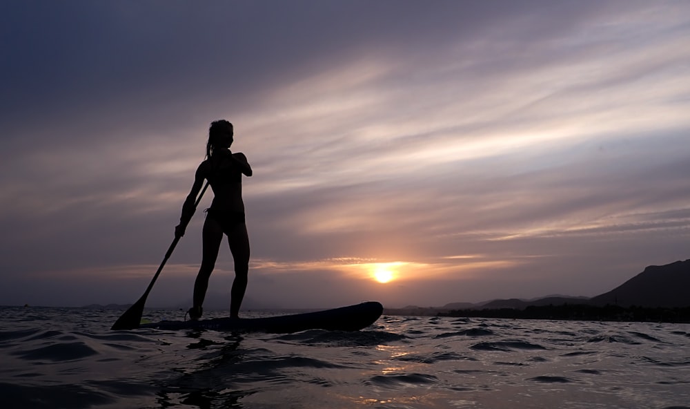 a woman standing on a paddle board in the ocean