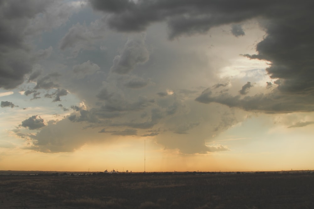 a large field with a sky filled with clouds