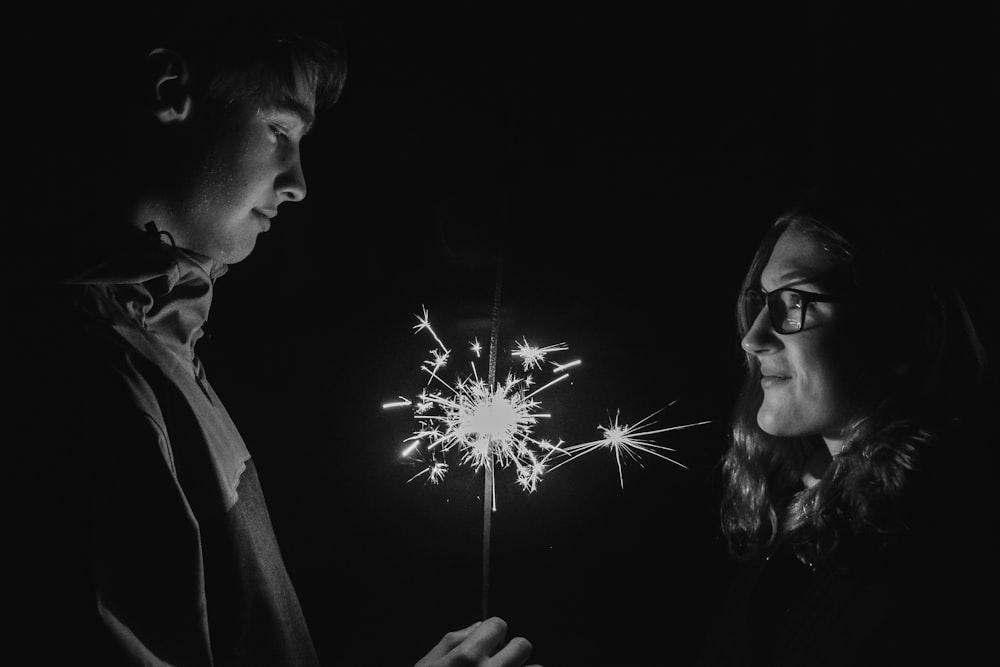 a man and a woman looking at a sparkler