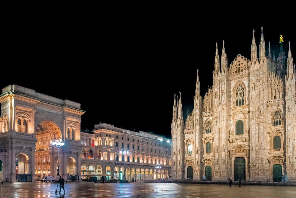 a cathedral lit up at night with people walking around