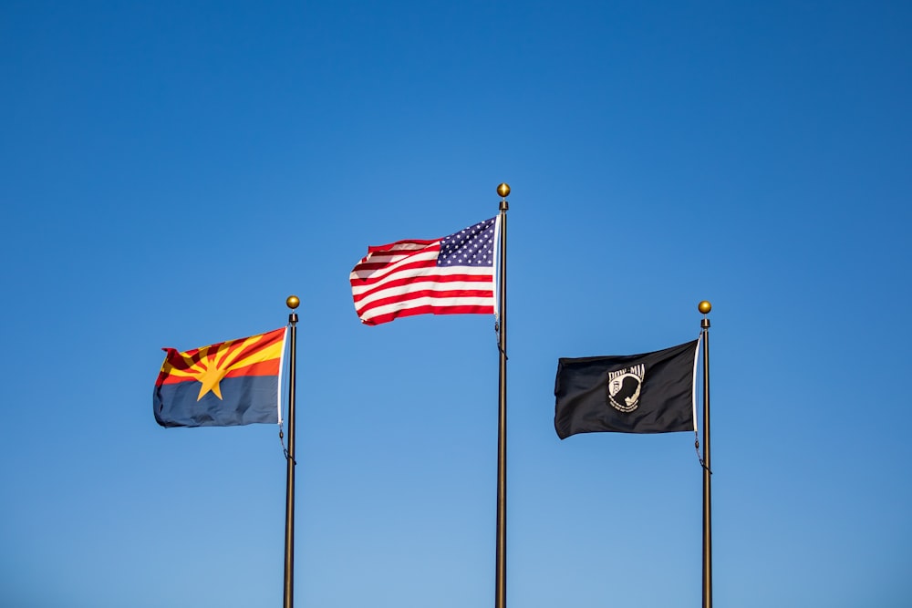 a group of three flags flying next to each other