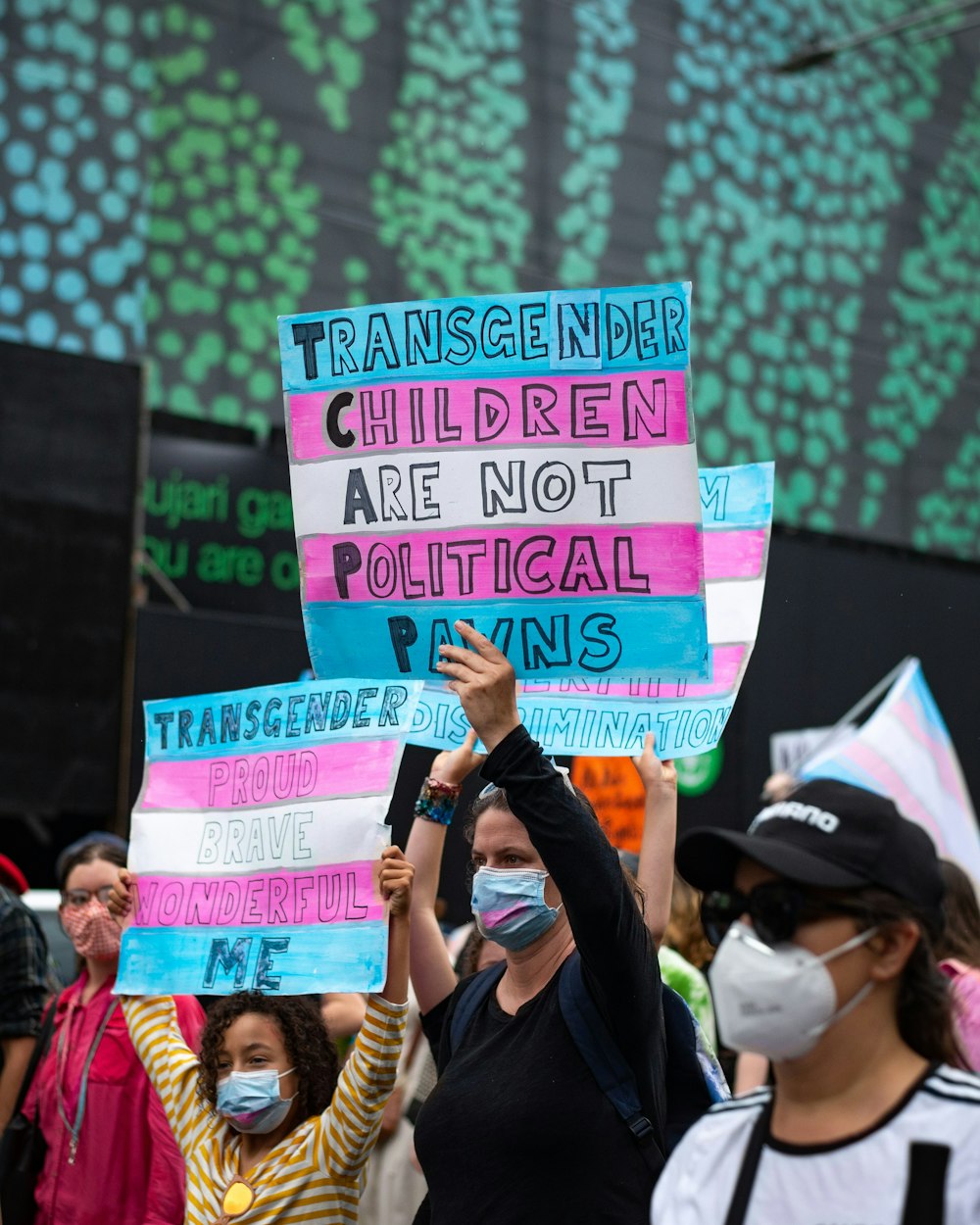 a group of people holding signs and wearing masks