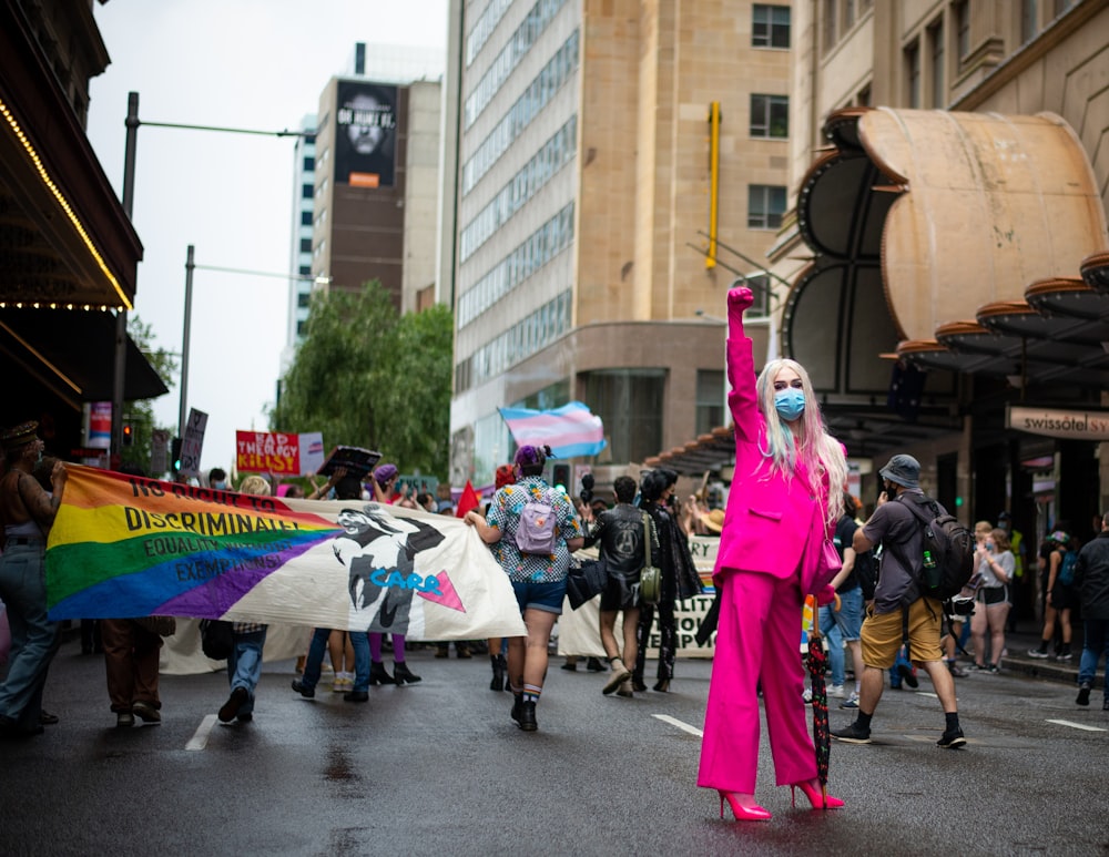 uma mulher em um terno cor-de-rosa segurando uma bandeira do arco-íris