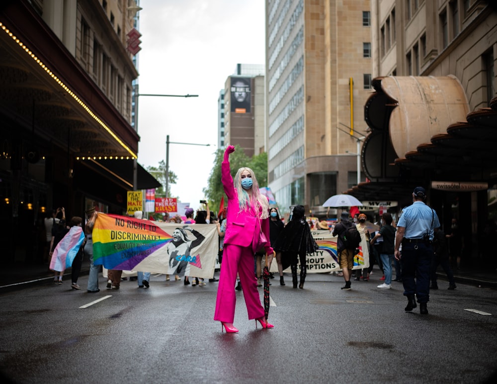 a woman in a pink suit holding a rainbow kite