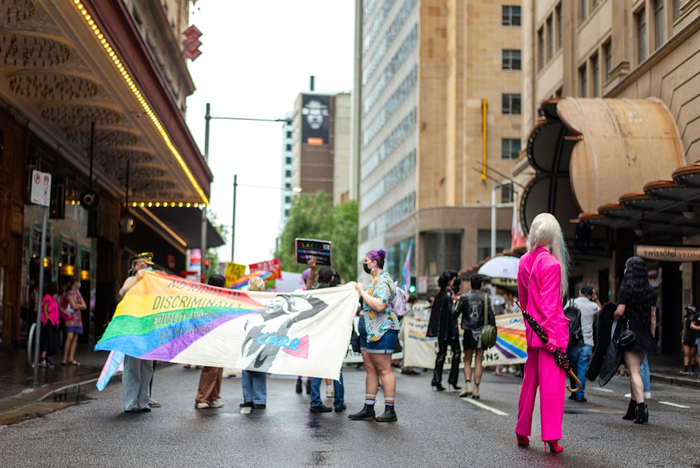 a group of people walking down a street holding a rainbow flag