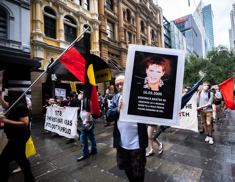 a group of people walking down a street holding signs