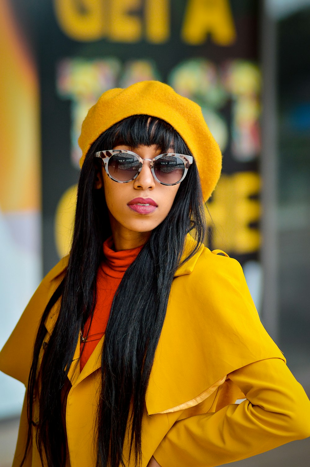 a woman wearing a yellow coat and sunglasses
