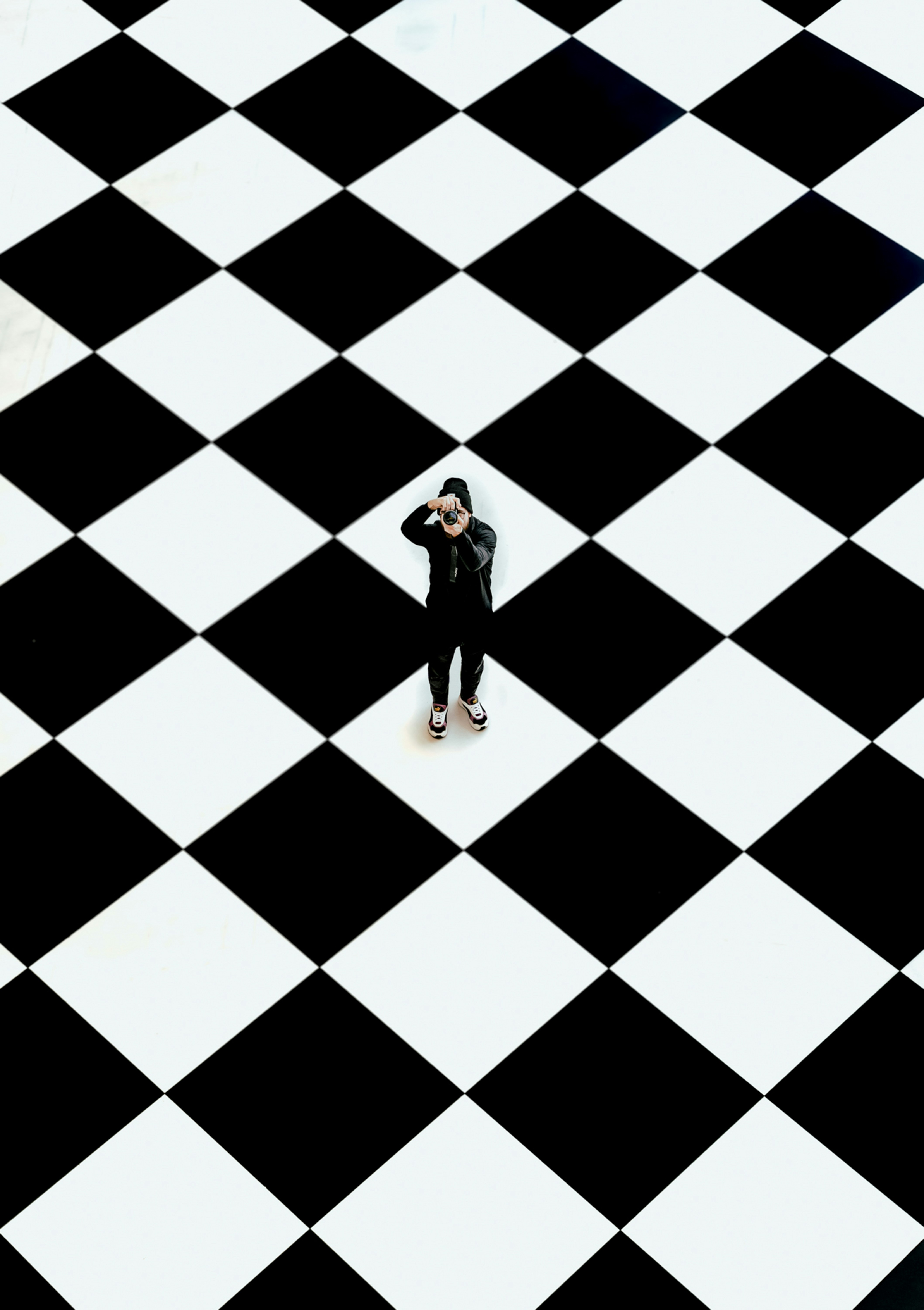 a person taking a picture of a black and white checkered floor