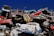 A pile of old, rusted cars stacked haphazardly on top of each other under a clear blue sky. The vehicles are in various stages of decay, with missing parts and visible damage.