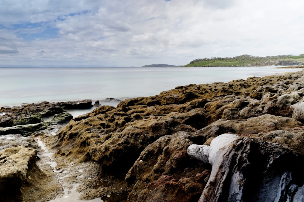 a rocky beach with a body of water in the background