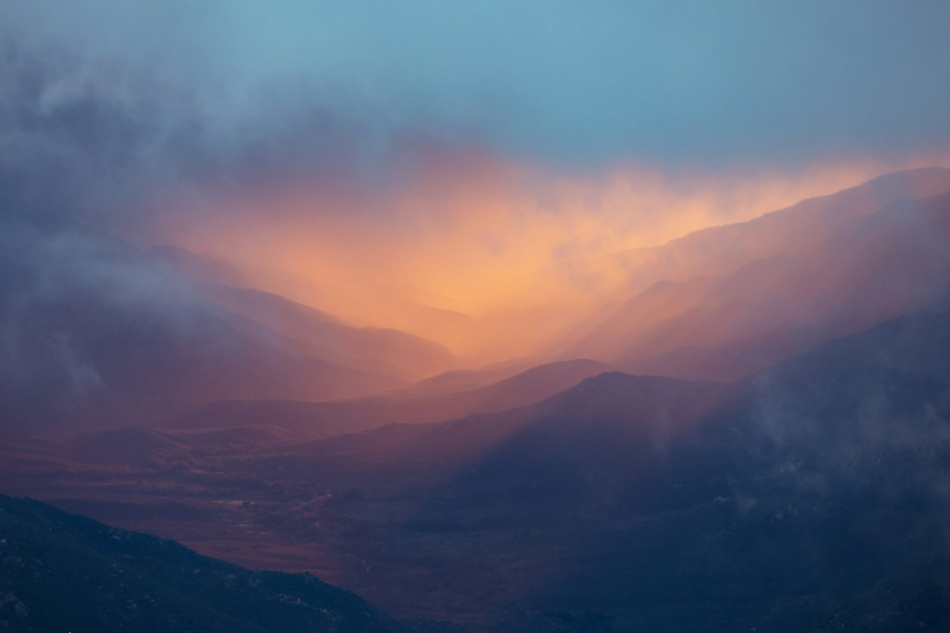 A sweeping landscape shot of golden clouds rolling over a misty mountain range, evoking a sense of wonder.
