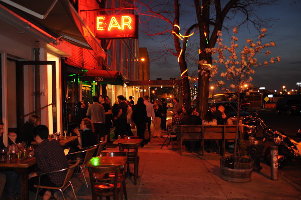 a group of people sitting at tables outside of a restaurant