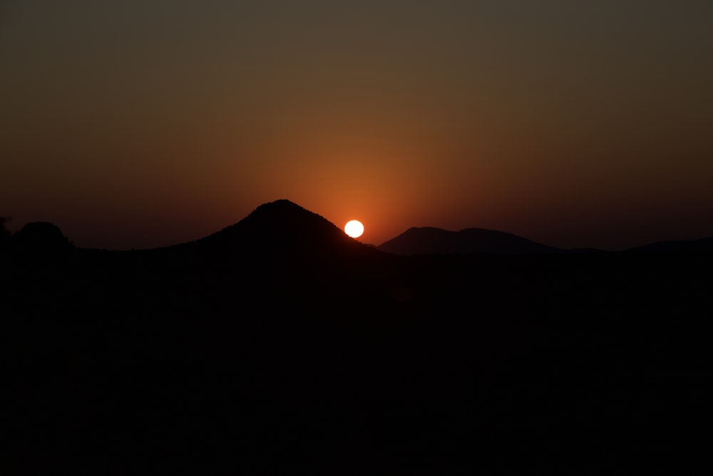 the sun is setting over a mountain range