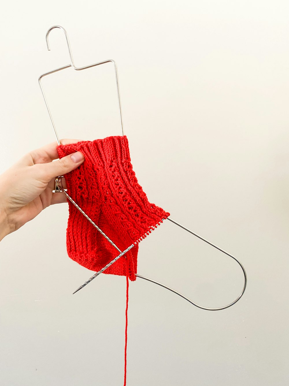 a hand holding a red piece of yarn