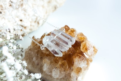 Delicate necklaces with crystals and floral accents displayed on a wooden surface.