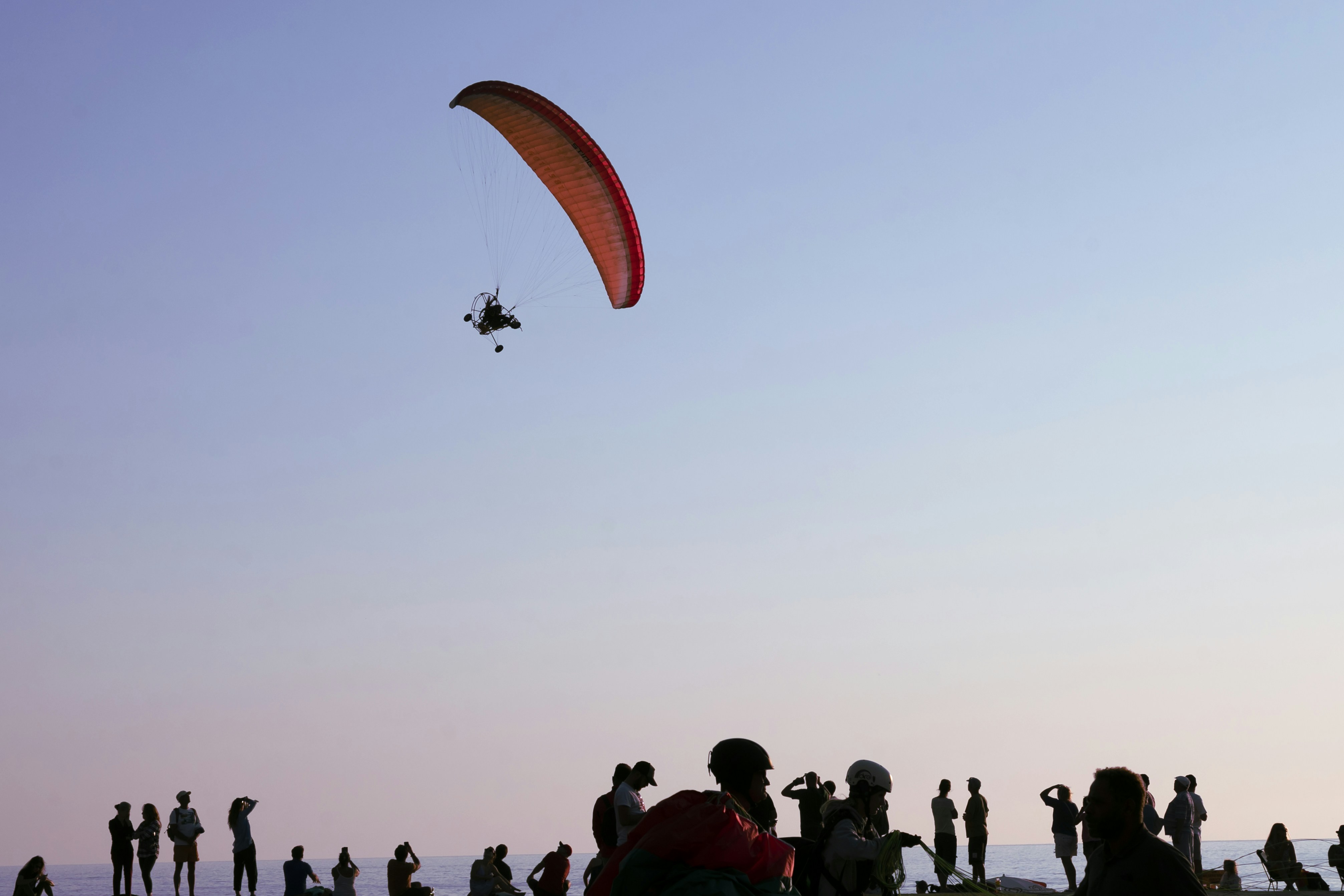 a group of people standing on top of a beach flying kites