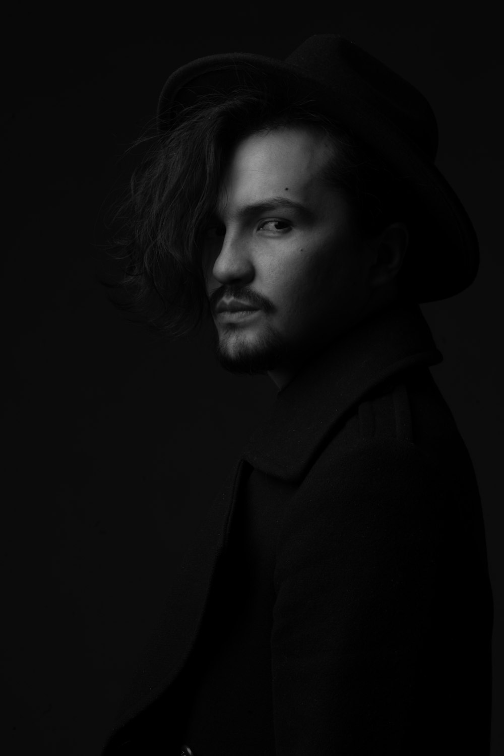 a black and white photo of a man wearing a hat