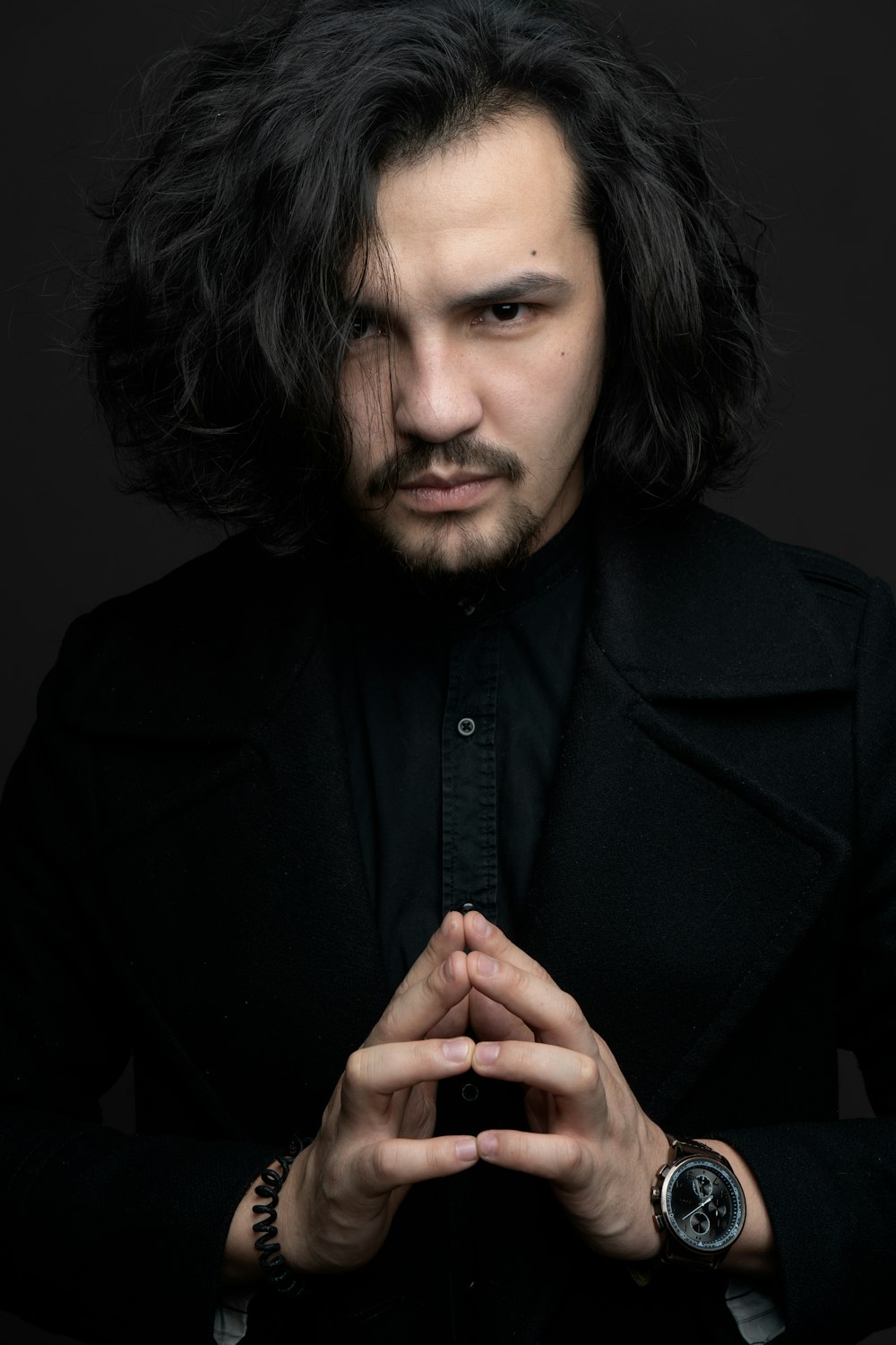 a man with long hair wearing a black coat