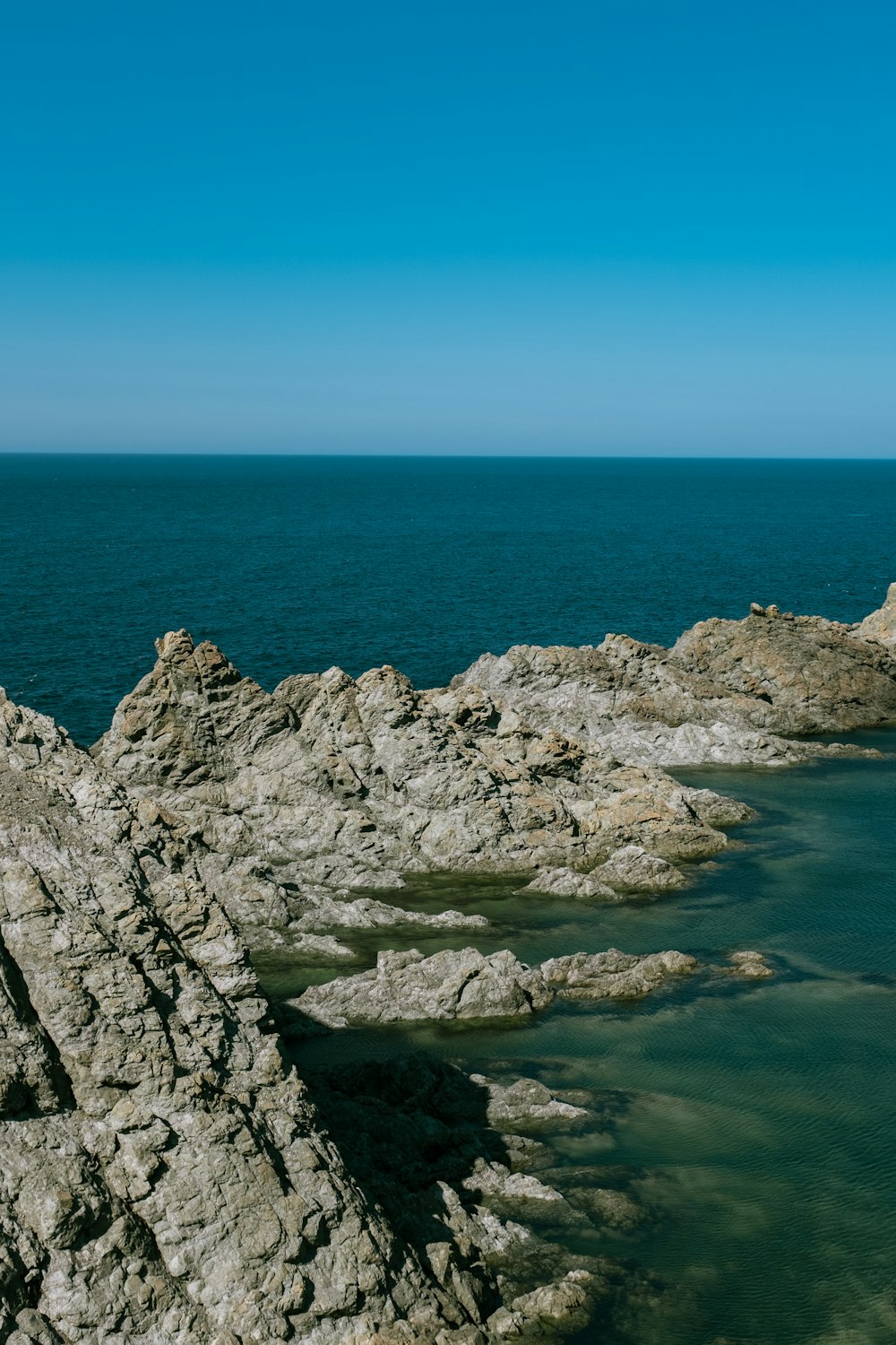 a man standing on top of a rocky cliff next to the ocean